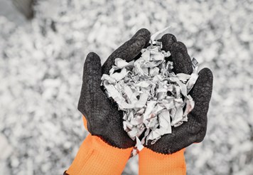 Two hands together holding small pieces aluminium scrap.